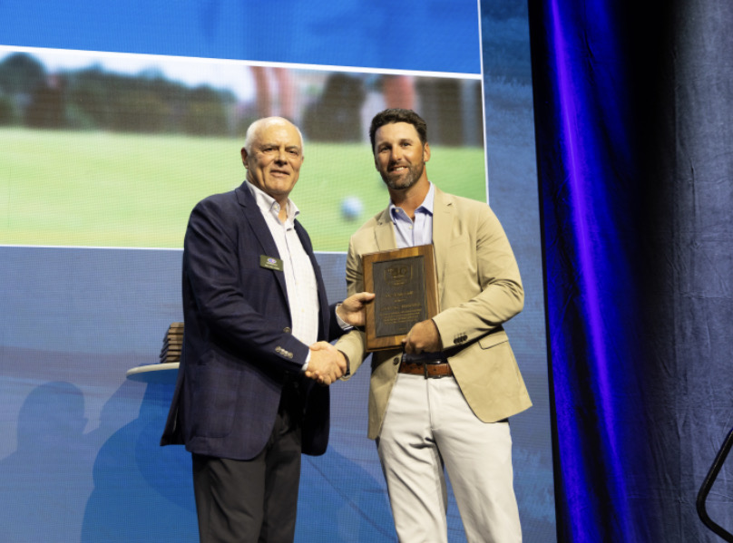 Two men shaking hands on stage during an award ceremony.