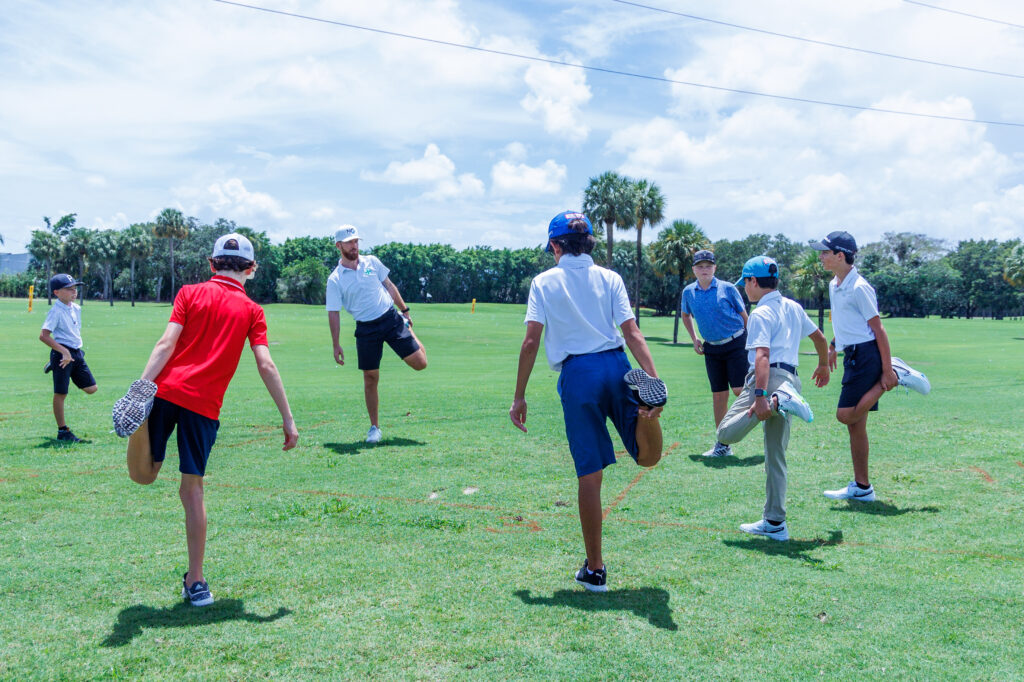 Children stretching before playing soccer on a sunny field.