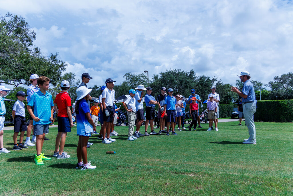 Group of people lined up on a golf course, preparing to play.