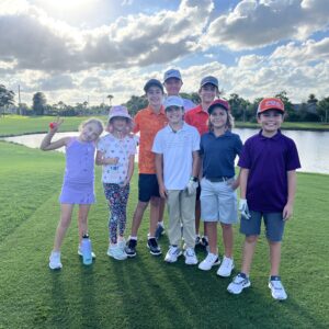 A group of boys posing on a golf course on a sunny day.