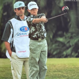 Golfer practicing swing with a caddy on a lush course.