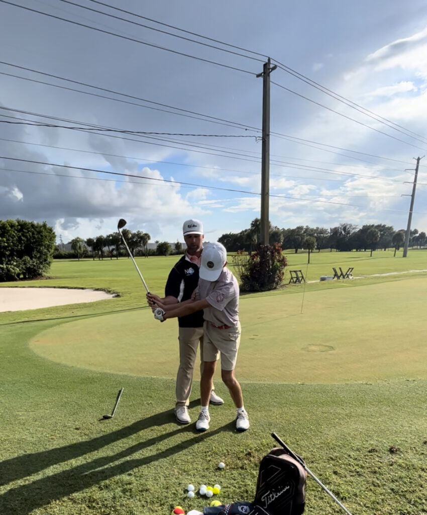 Two golfers share a friendly moment on the green under a partly cloudy sky.